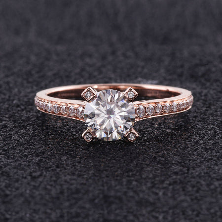 round brilliant moissanite engagement ring in solid 14k rose gold featuring a hidden halo setting and pavé accent band.