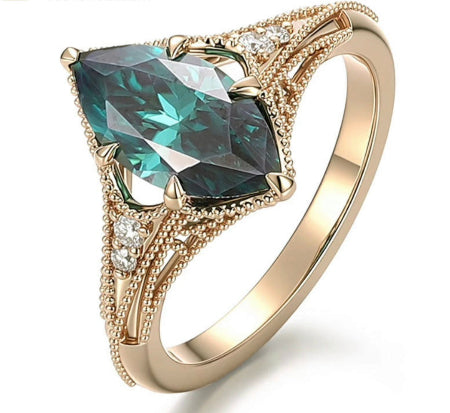green marquise cut moissanite engagement ring in yellow gold with vintage split shank and accent diamonds worn on finger.