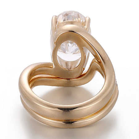 oval cut moissanite bridal ring set featuring a twisted bypass engagement ring with a matching curved pavé diamond wedding band in solid rose gold.