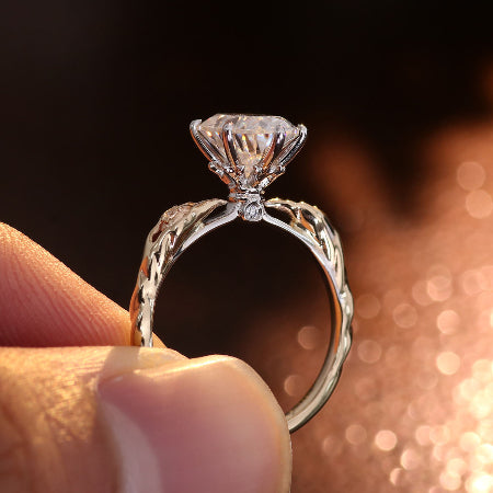2ct oval cut moissanite engagement ring in 14k rose gold with vintage leaf side accents and six-prong solitaire setting for women.