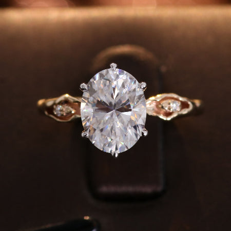 2ct oval cut moissanite engagement ring in 14k rose gold with vintage leaf side accents and six-prong solitaire setting for women.