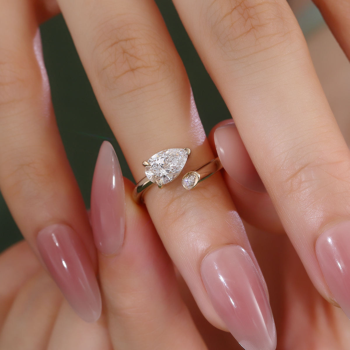 pear cut moissanite engagement ring in 14k yellow gold with modern open wrap design and bezel accent, perfect for proposal, wedding or promise ring
