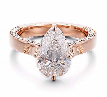 Pear cut moissanite engagement ring in solid 14K rose gold featuring pavé accents and engraved leaf details in a nature-inspired solitaire setting.